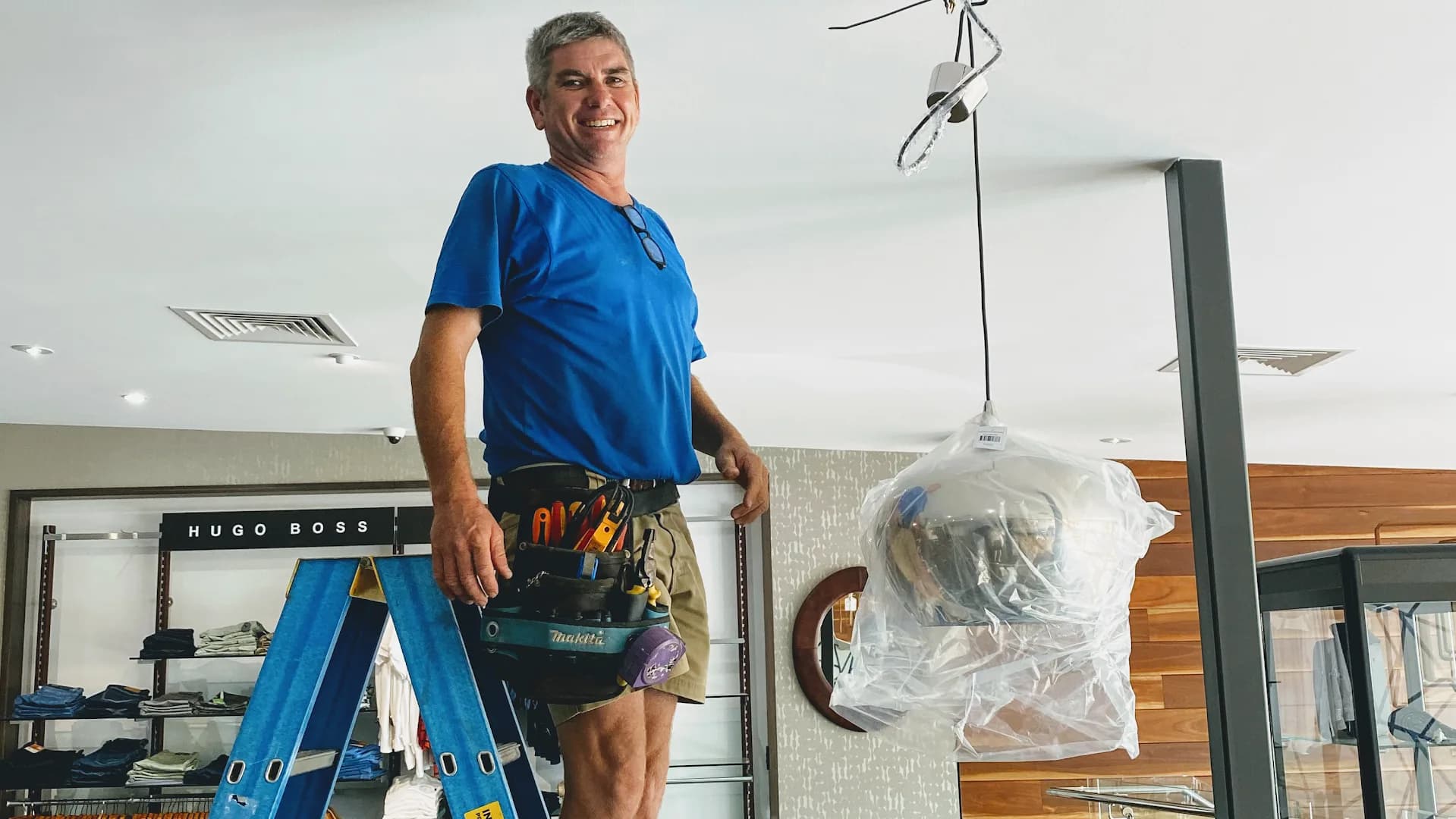Brendan Eggins installing commercial lighting at a Darwin retail store