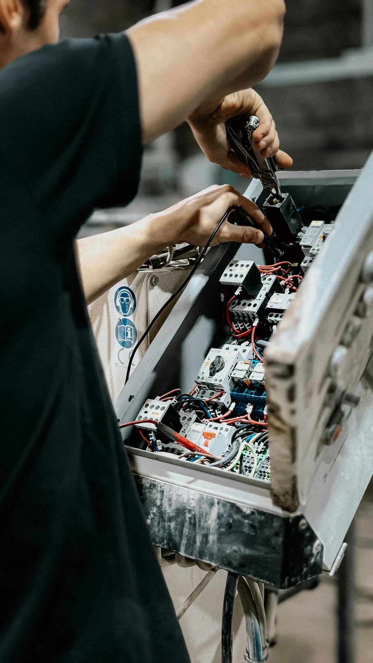 Technician adjusting wires in electrical control panel